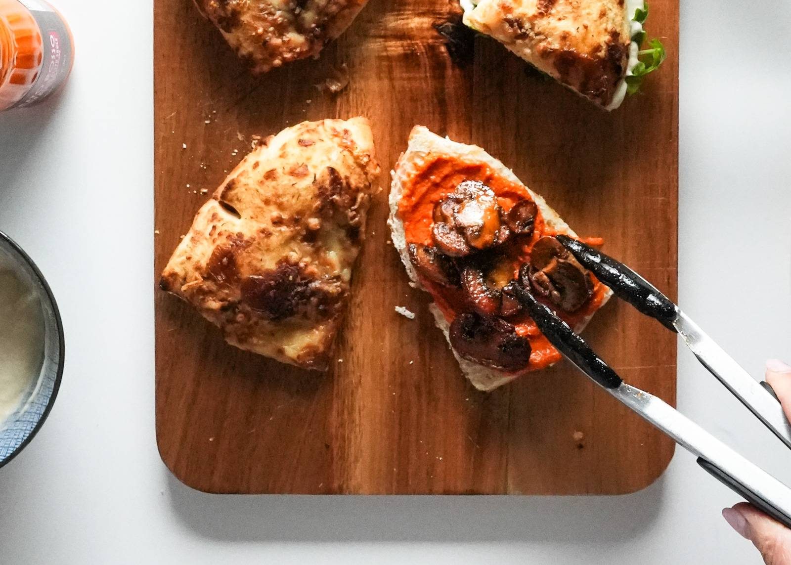Adding mushrooms and sauce to bread.