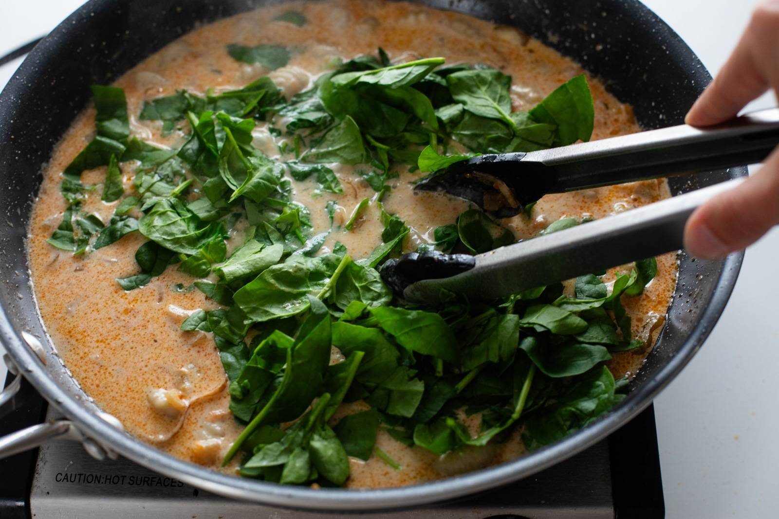 Adding spinach to skillet.