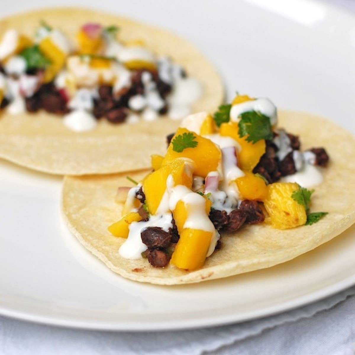 Mango black bean tacos with a creamy coconut sauce drizzled over the top.